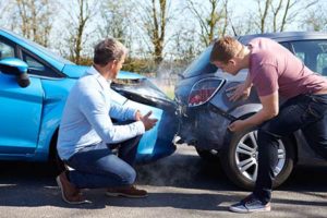 Two men looking at the damage to their car bumpers after a fender bender